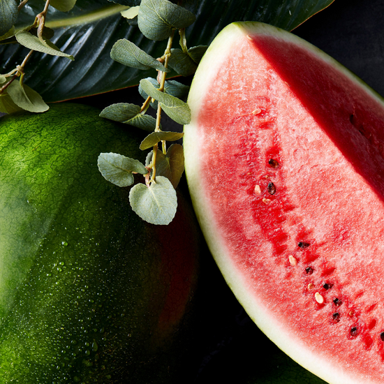 A close-up of watermelon and eucalyptus leaves on a black surface on Spa Circle Brands product listing page.