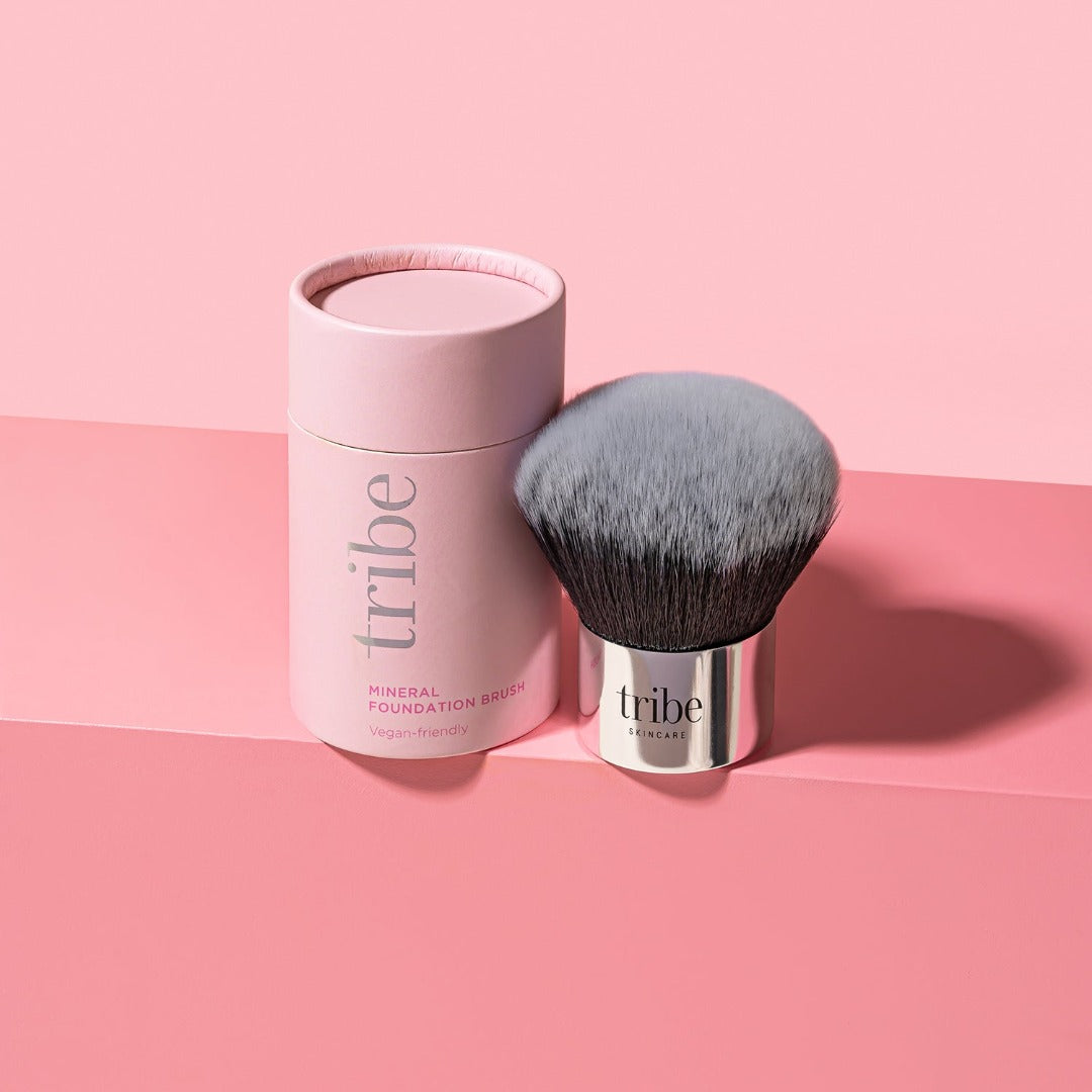 Tribe Mineral Makeup Brush next to its pink jar, resting on a soft pink background, showcased on Spa Circle Brands' product listing.